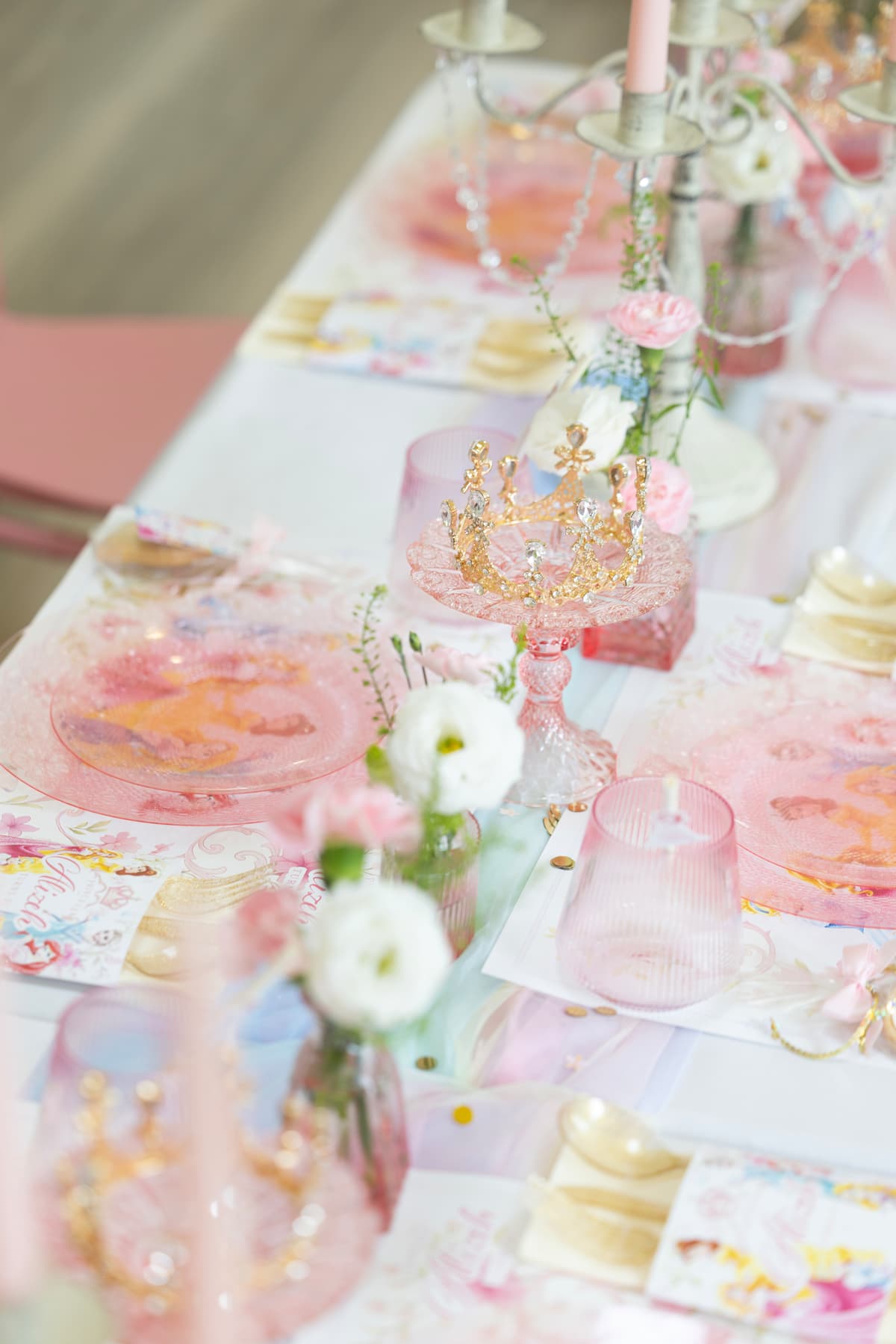 Princess-themed kids table styling with gold crowns, pink glassware, and flowers