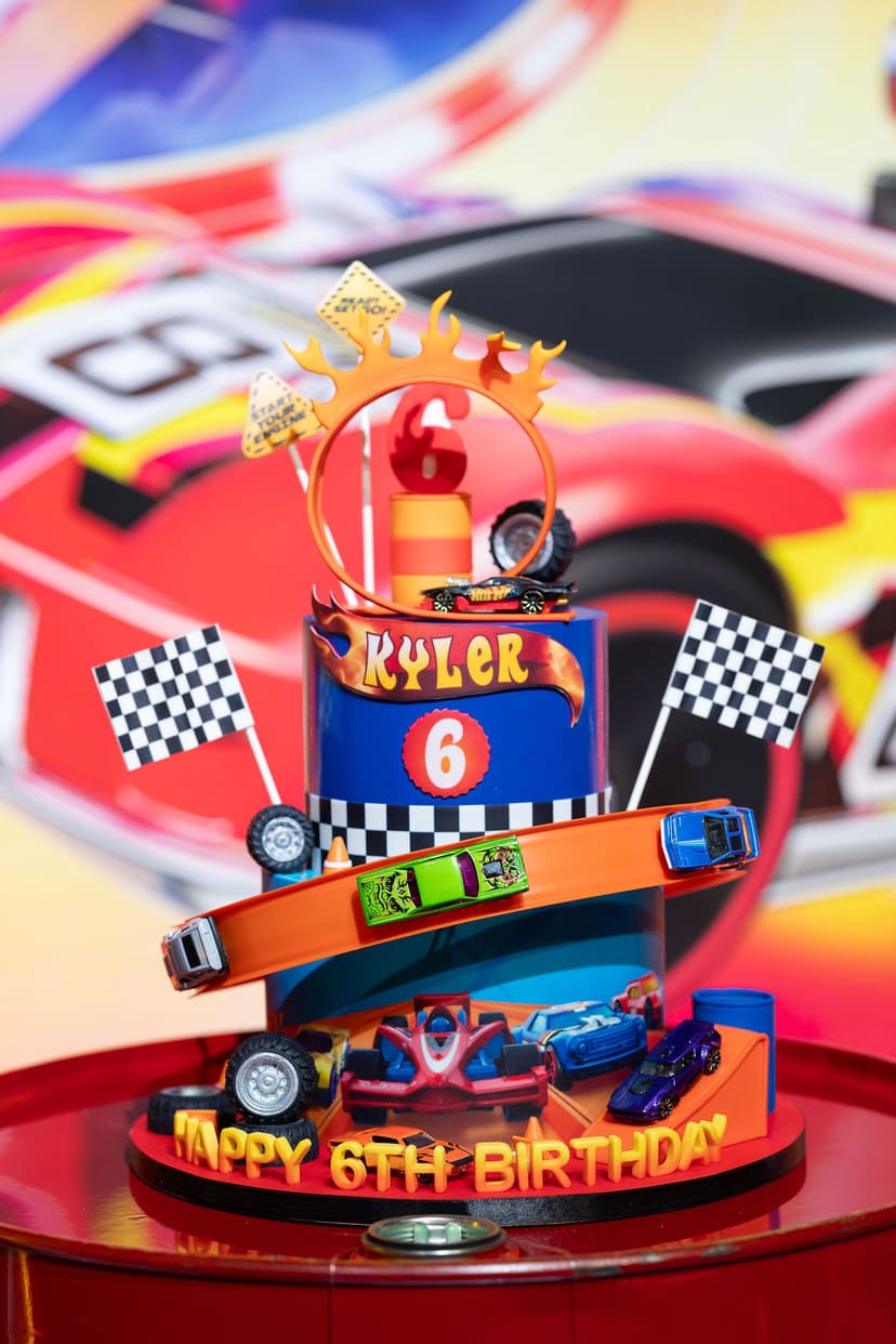 Hot Wheels themed multi-tier cake with toy cars and checkered flags