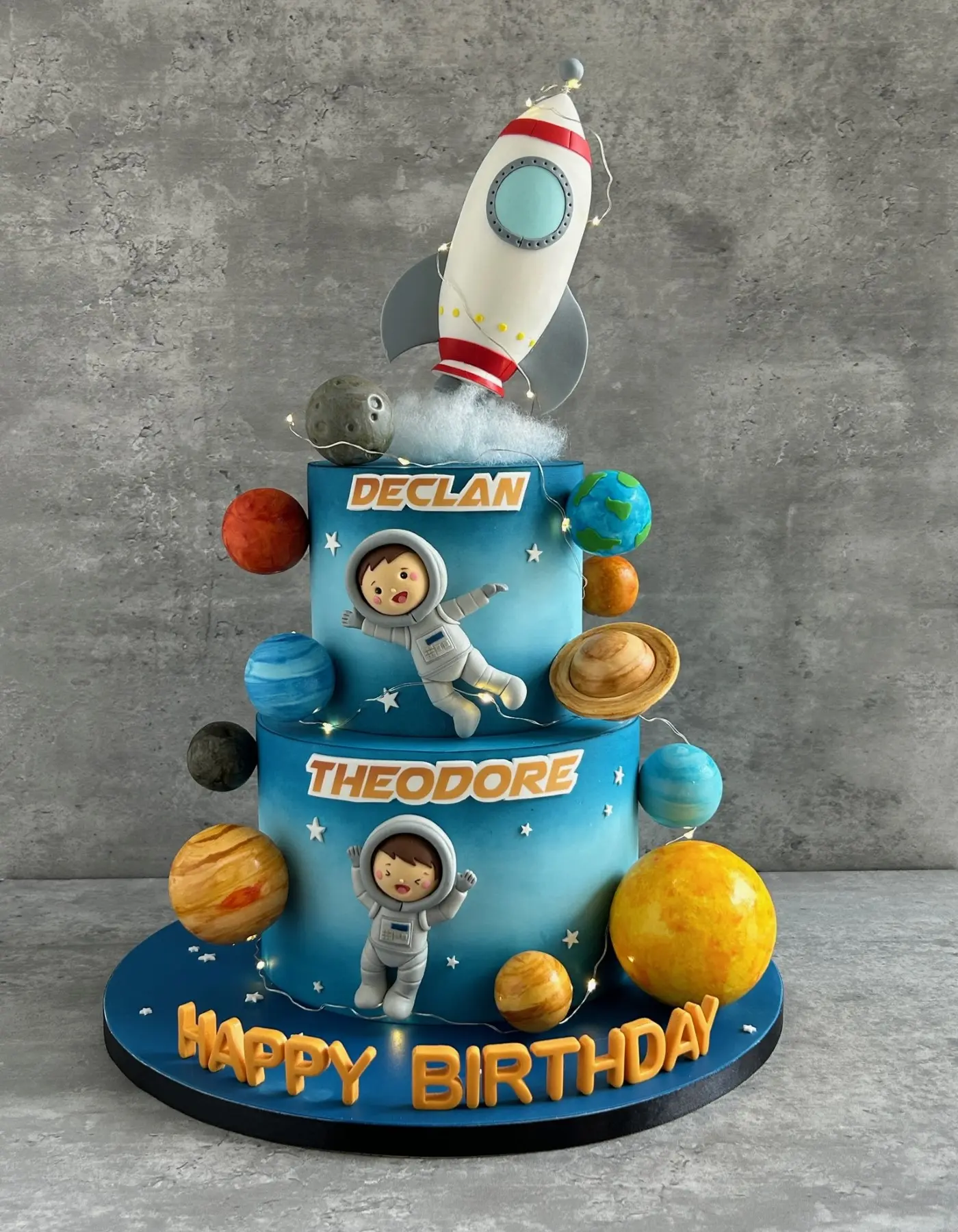 Outer space two-tier birthday cake with rocket, astronauts and planets